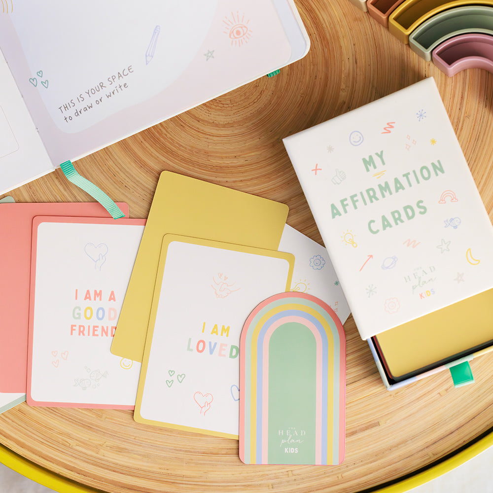 The Head Plan Kids Affirmation Cards laid out on table in colourful lifestyle setting