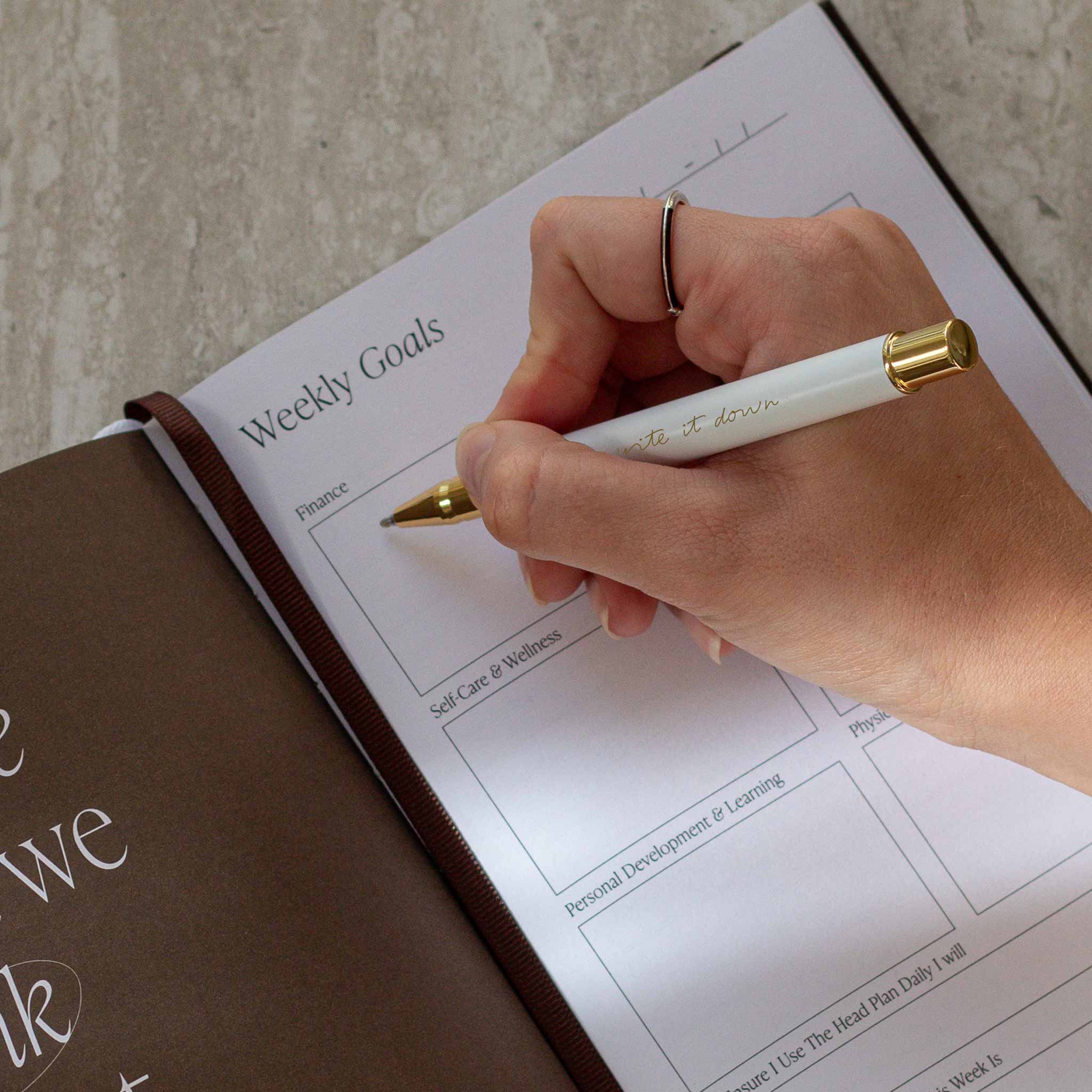 The Head Plan Pen Set white pen with gold accents writing on notebook page in journal